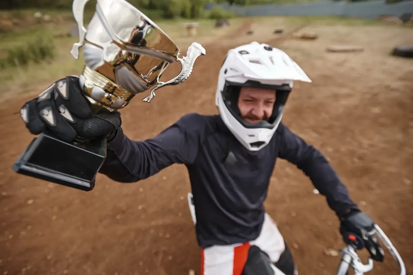 Motocross rider holding up a trophy on a dirt track, representing MX Trophies custom awards