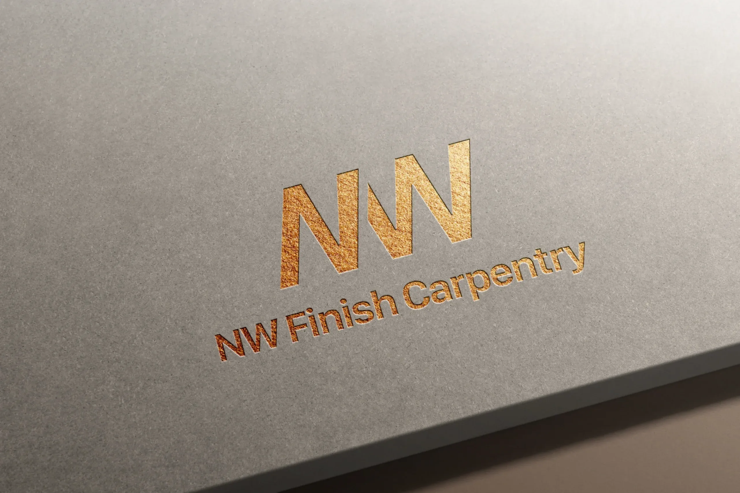 Gold foil embossed NW Finish Carpentry logo on smooth gray cardstock with saw blade-inspired angular NW monogram above the company name in metallic serif typography