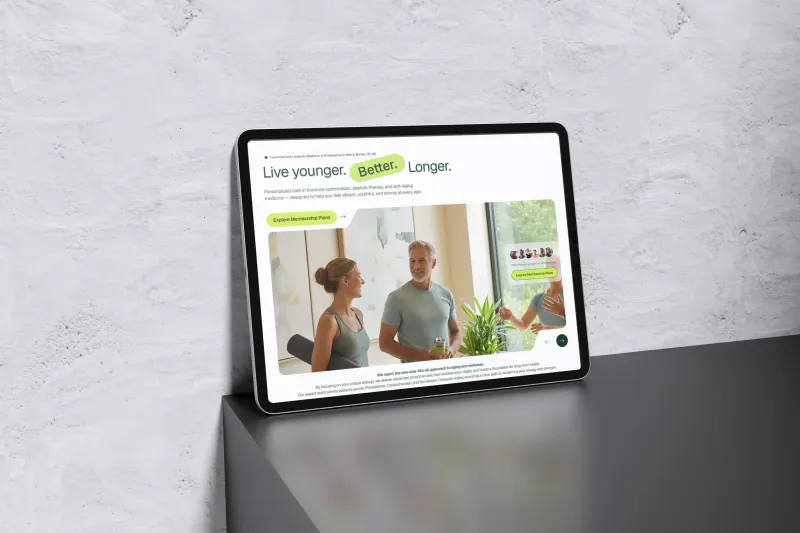 iPad mockup showing the Younger Me MD website redesign with a clean hero section featuring Live younger Better Longer tagline, lifestyle photography of a couple in a wellness setting, and membership plan CTA in a green and white color scheme